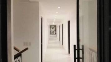 A corridor with a staircase on the left and a glass door on the right.