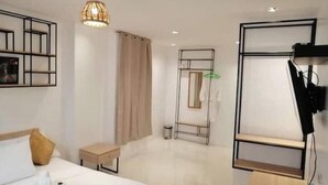 A modern hotel room with a bed, bedside table, and a hanging light fixture. - Hotel Rupert A -Deluxe Suite King Bedroom (Aurora)
