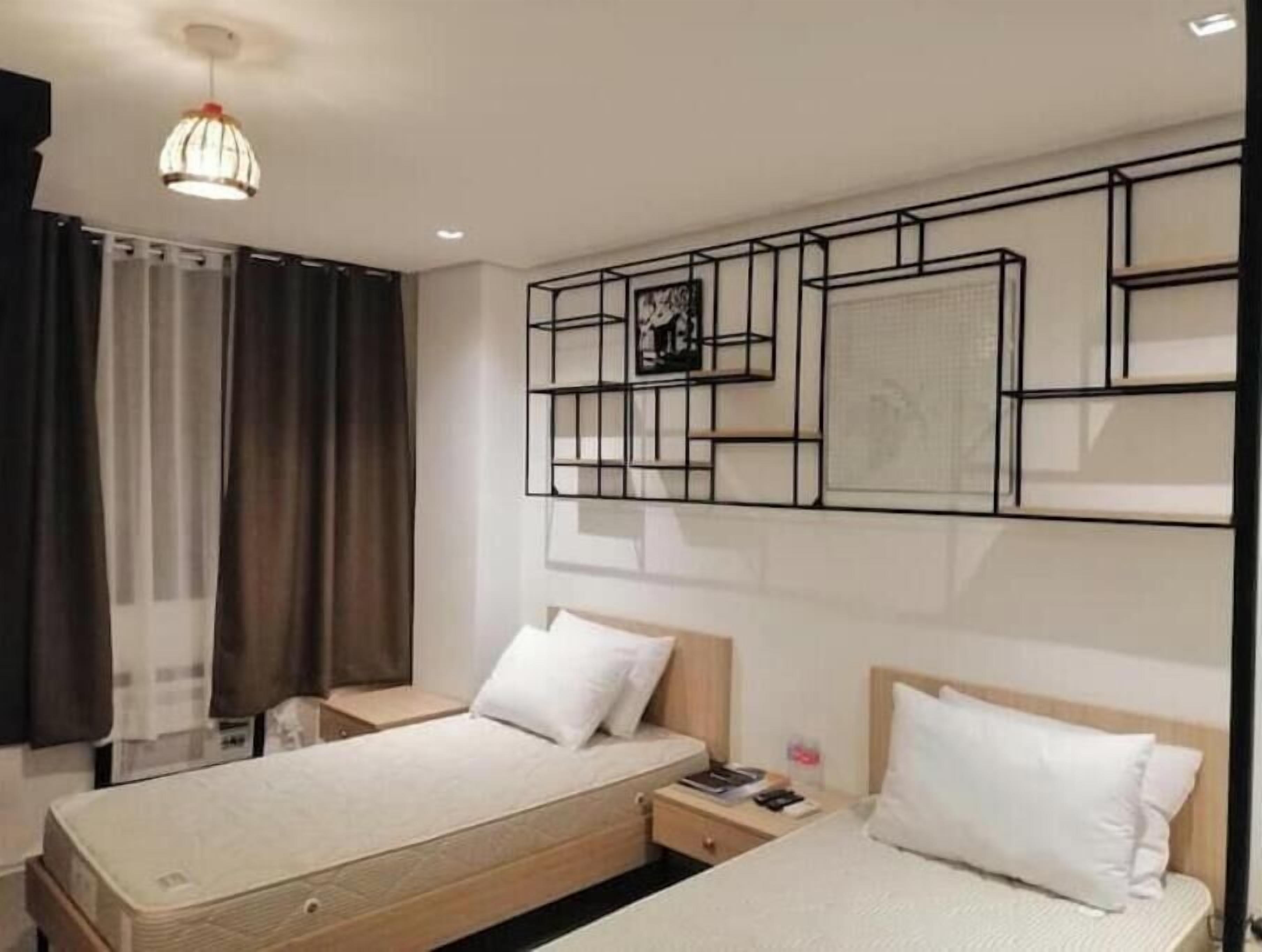 Una camera d'albergo con due letti, un'opera d'arte moderna a parete e un lampadario.