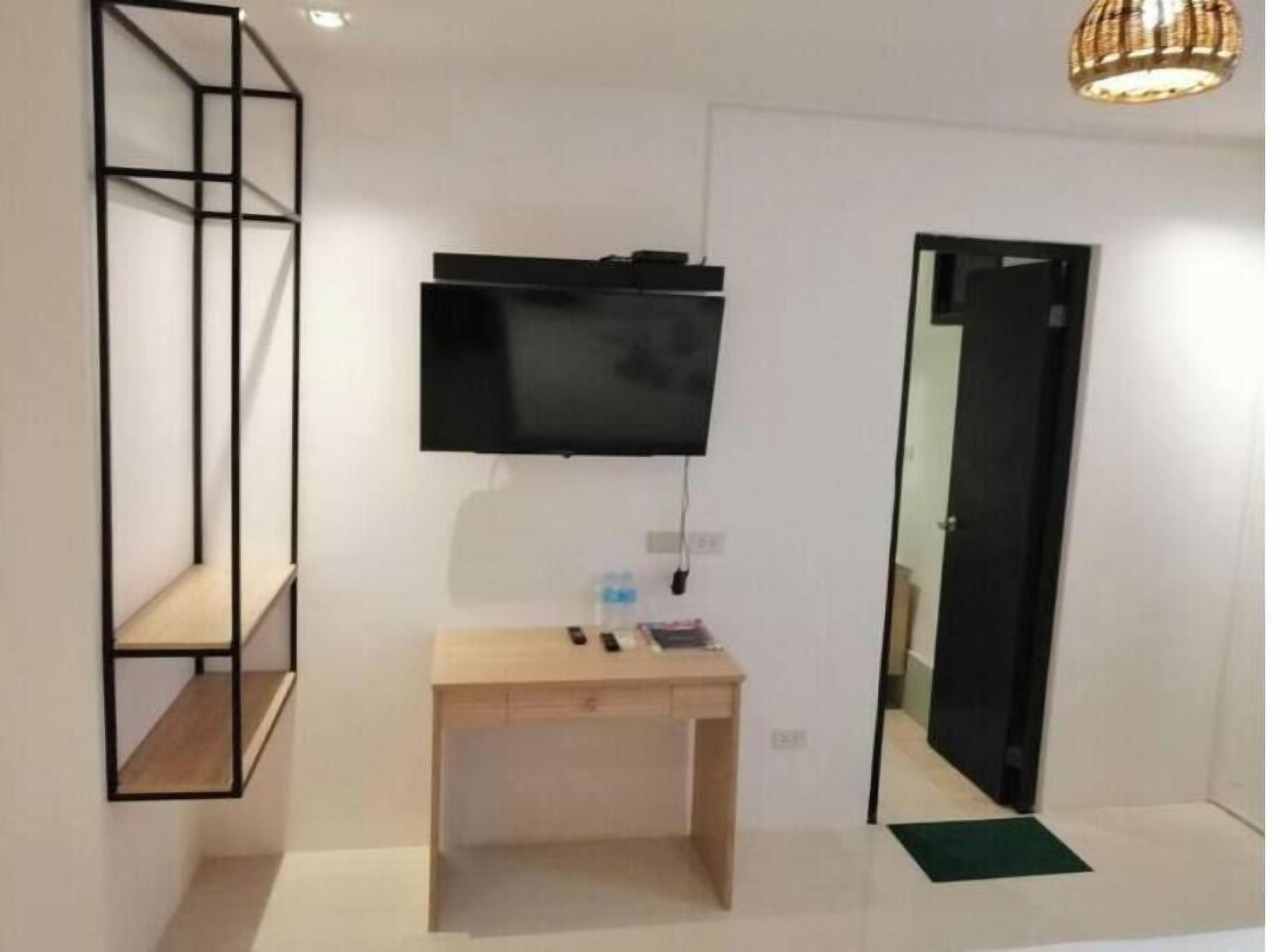 A modern room with a wooden desk, a mounted TV, and a mirror.