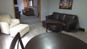 A living room with a brown leather sofa, a patterned armchair, and a dining table.