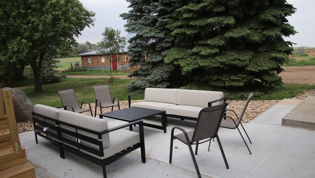 Une terrasse extérieure avec un canapé, des fauteuils et une table.