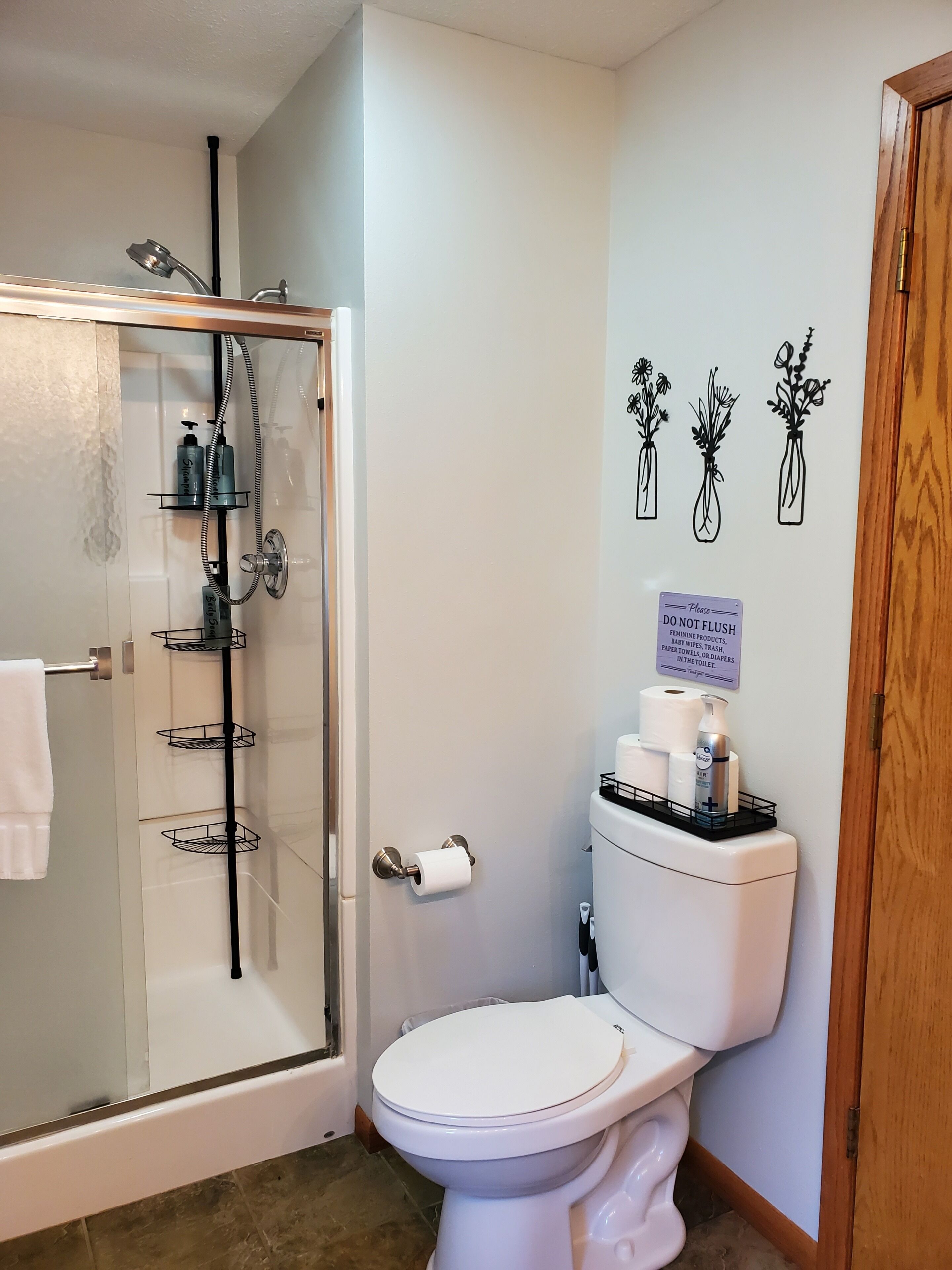 Une salle de bain avec une douche à parois de verre, des toilettes et un panneau fixé au mur.