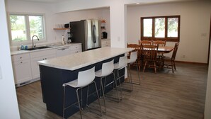 Une cuisine moderne dotée d’un îlot central, de tabourets de bar et d’un coin repas avec des chaises en bois.
