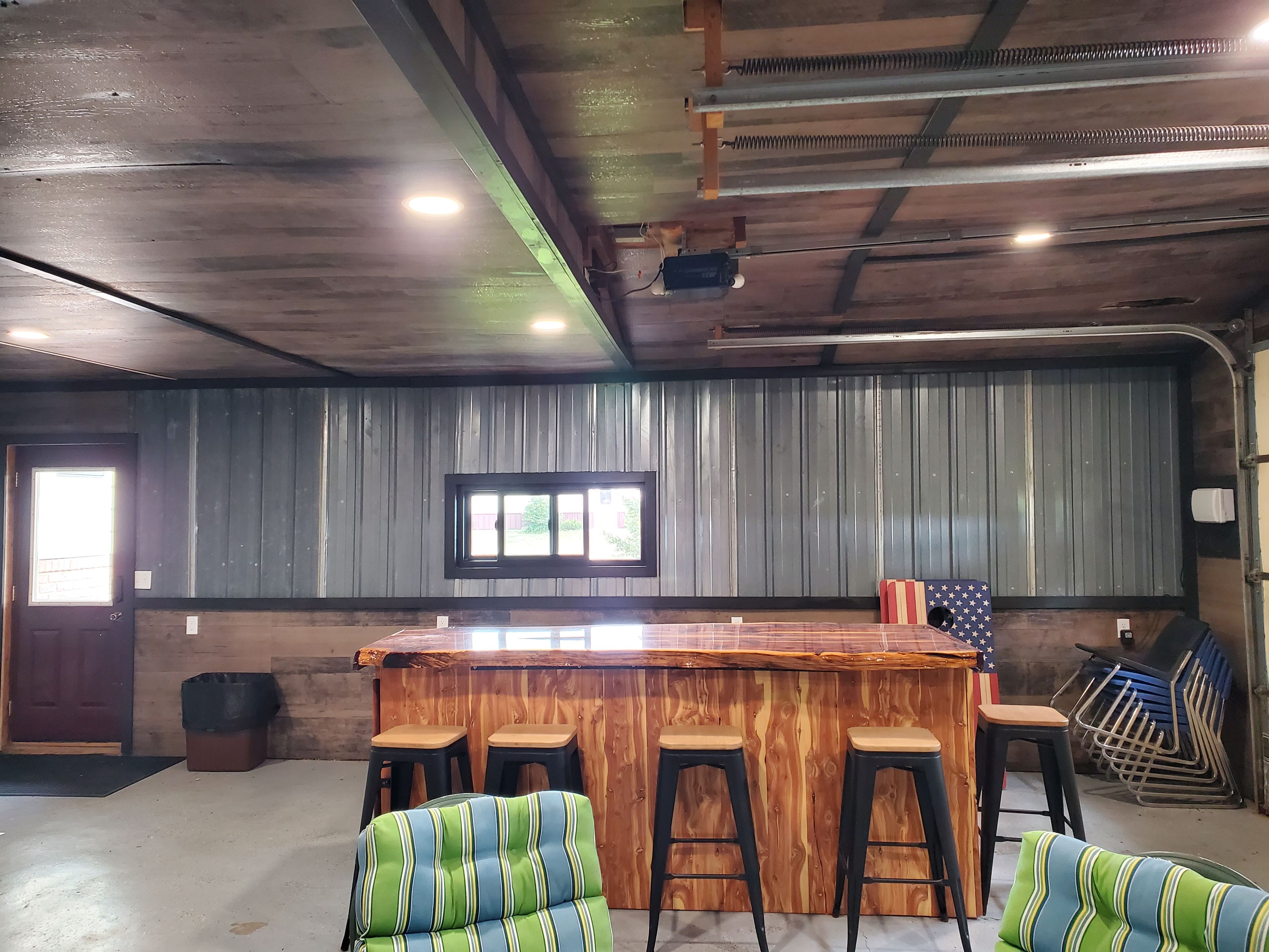 A bar area with stools, a wooden counter, and a window with a view.