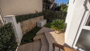 A residential building with a stone wall, a small garden with a potted plant, and a staircase leading to an upper level. - Terrace Haven Hvar (Hvar)