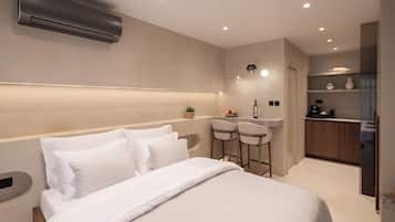 Una habitación de hotel moderna con una cama grande, una kitchenette pequeña y un área de bar.