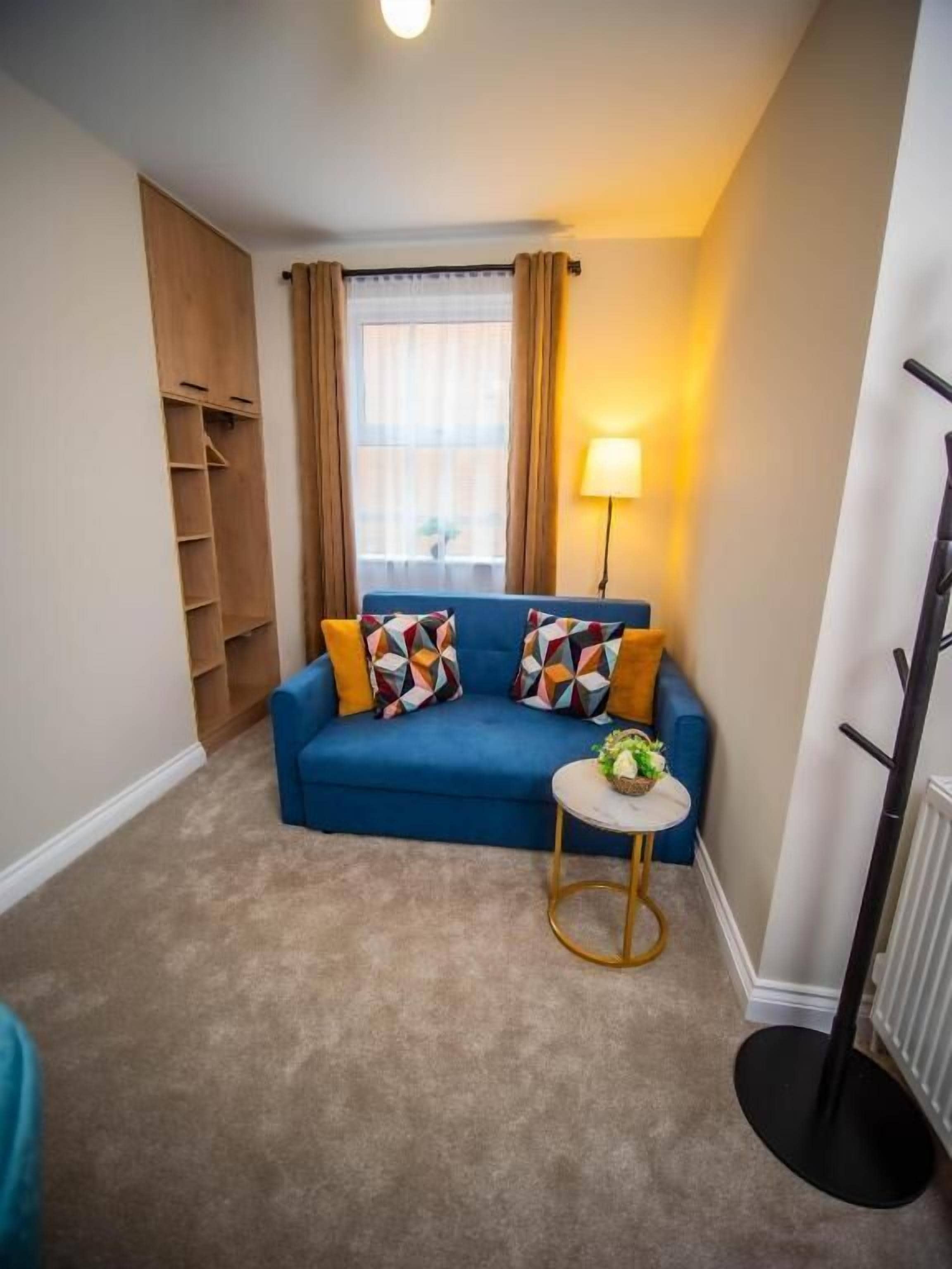 A cozy living room with a blue sofa, a small round table, and a lamp.