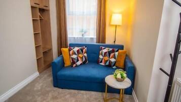 A cozy living room with a blue sofa, a small round table, and a lamp.