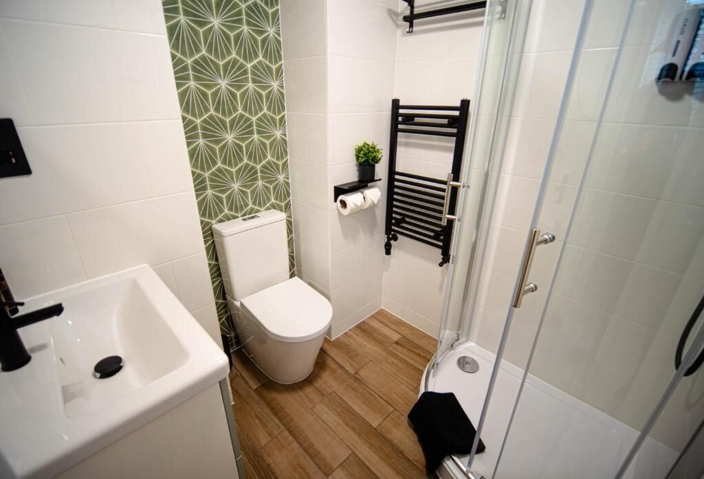 Un baño con lavamanos, inodoro y ducha blancos.
