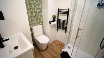 Un baño con lavamanos, inodoro y ducha blancos.