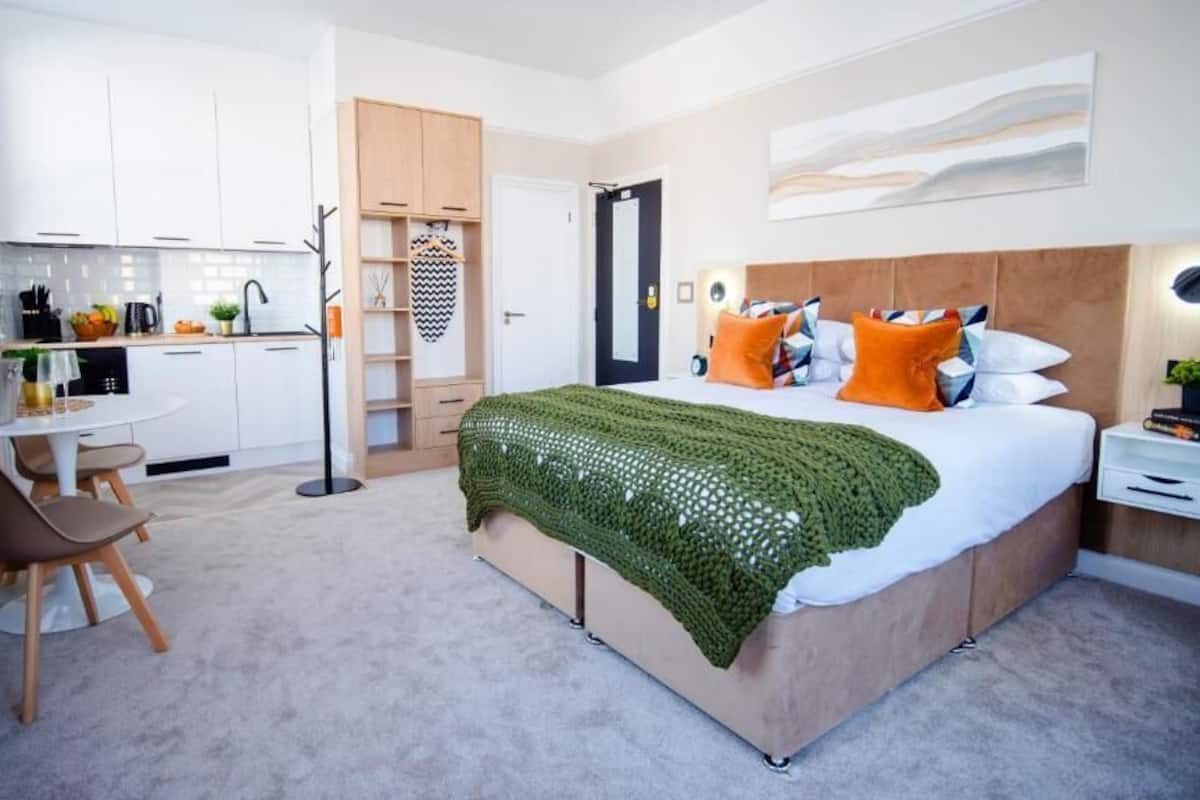 Un dormitorio moderno con una cama grande, una mesita de noche y vistas a la cocina.