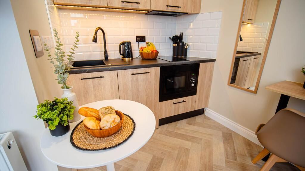 Een kleine keuken met een wit aanrecht, zwarte apparaten en houten keukenkastjes.