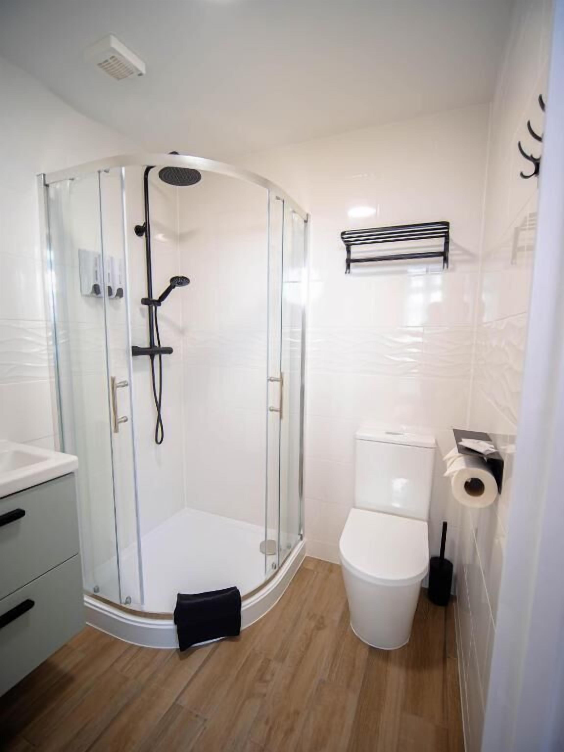 Un baño moderno con ducha envuelta en vidrio, inodoro y lavabo.