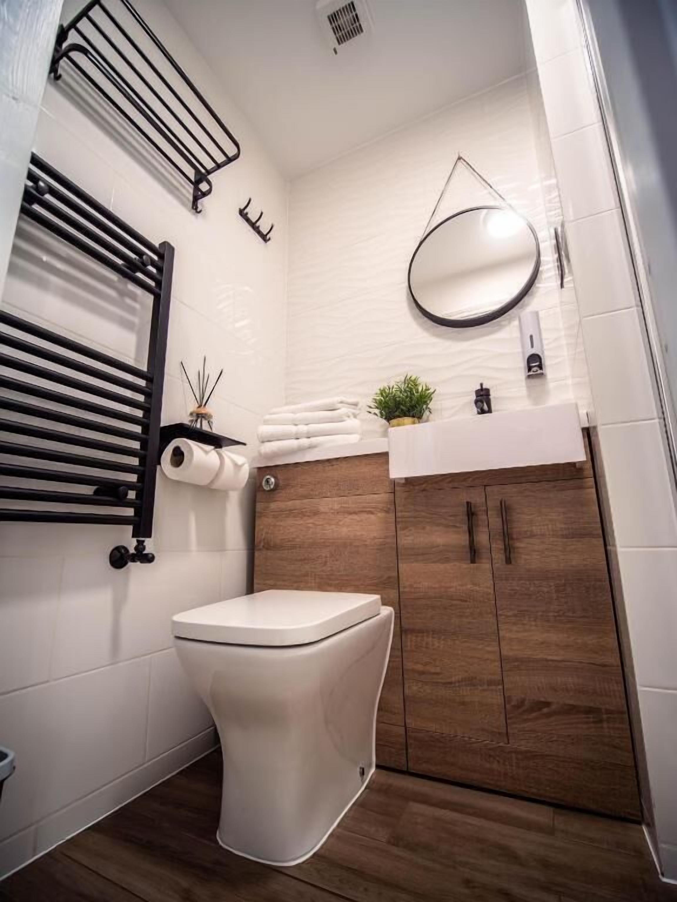 Ein modernes Badezimmer mit Toilette, Handtuchhalter, Spiegel und Waschbecken.