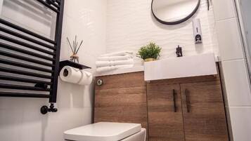 A modern bathroom with a toilet, a towel rack, a mirror, and a sink.