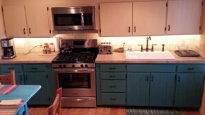 A fully stocked kitchen with stainless steel appliances, a microwave, toaster, and a sink. - Historic Mill House Unit 4 (Taos)