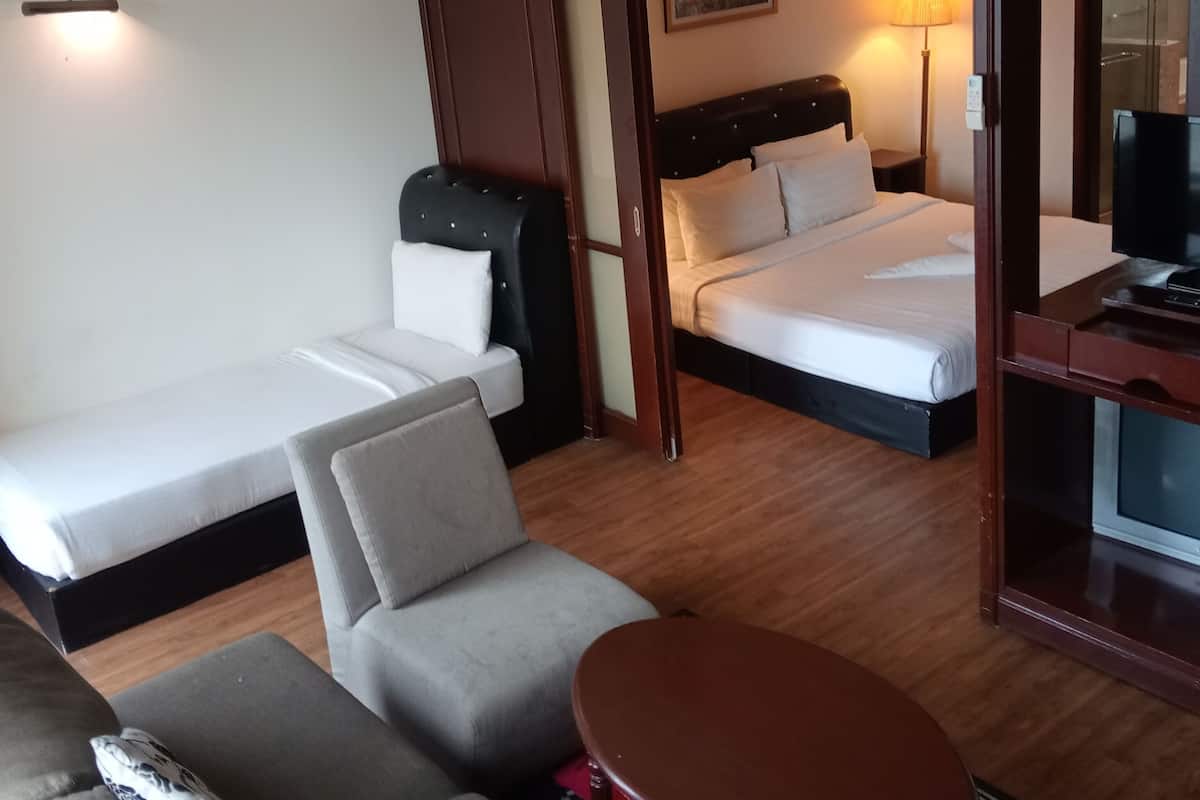 A hotel room with a bed, a sofa, a small table, and a TV.