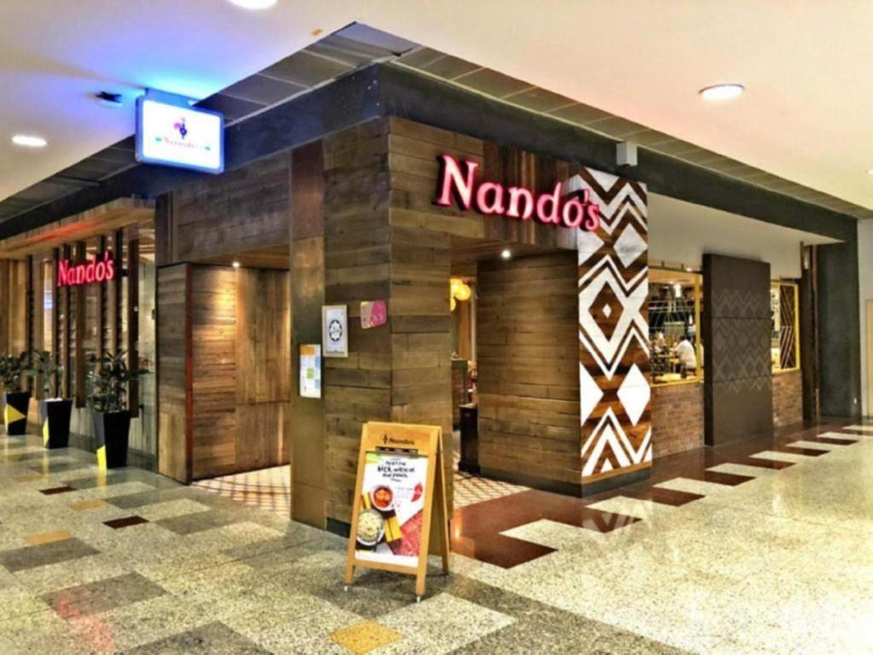 A restaurant named 'Nandos' with a modern interior design, featuring a checkered floor and wooden accents.