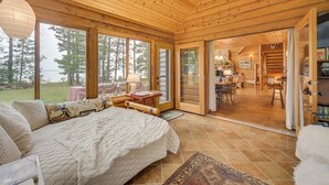 A log cabin bedroom with a large bed, a dining area, and a view of the outdoors.