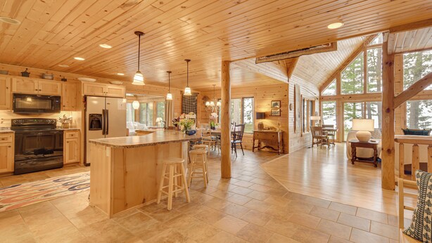 A spacious kitchen with wooden cabinets, a large island with stools, and a dining area with a table and chairs.