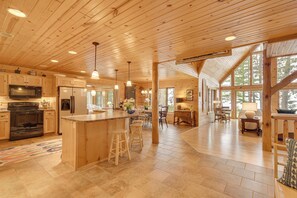 Une cuisine spacieuse avec des meubles en bois, un grand îlot central doté de tabourets et un coin repas avec une table et des chaises.