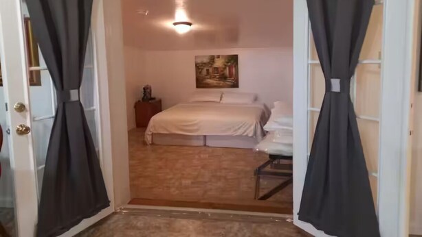 A bedroom with a bed, a nightstand, a lamp, and a painting on the wall.