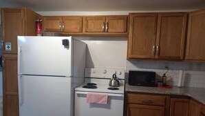 A kitchen with wooden cabinets, a white refrigerator, a stove, and a microwave.