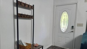 A hallway with a coat rack, a wicker basket, and a door with a stained glass window.
