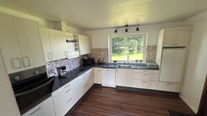Una cocina funcional con armarios blancos, encimera negra, horno empotrado y ventana con vistas al exterior.