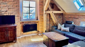 Una sala de estar acogedora con pared de ladrillo, chimenea, televisor y sofá.