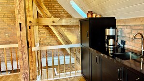 Una cocina con pared de ladrillo, escalera de madera y cafetera.