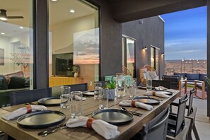 A dining table set for four with plates, cutlery, and glasses, overlooking a desert landscape. - Powell's Edge Retreat - Hot tub+ Pickle-ball + Home Gym + Lake Views + Sleeps 20 (Page)
