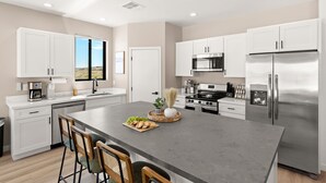 Una cocina moderna con armarios blancos, electrodomésticos de acero inoxidable y una isla grande con asientos.