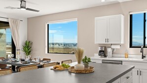 Una cocina moderna con una isla grande, armarios blancos y vistas al paisaje.