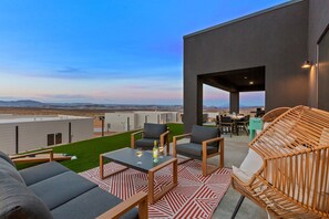 An outdoor patio with seating, a table with glasses, and a view of the landscape. - Powell's Edge Retreat - Hot tub+ Pickle-ball + Home Gym + Lake Views + Sleeps 20 (Page)