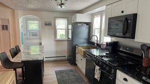 A modern kitchen with a central island, black appliances, white cabinets, and a dining area with chairs.