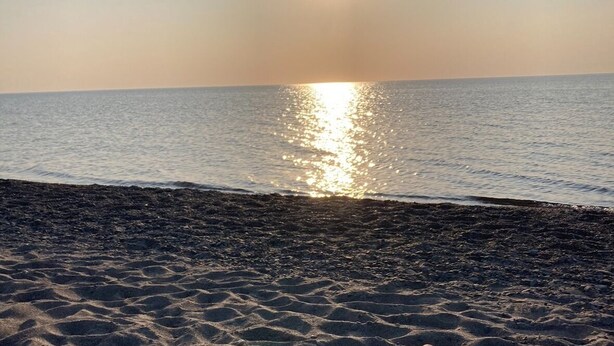 A beach with the sun reflecting on the water.