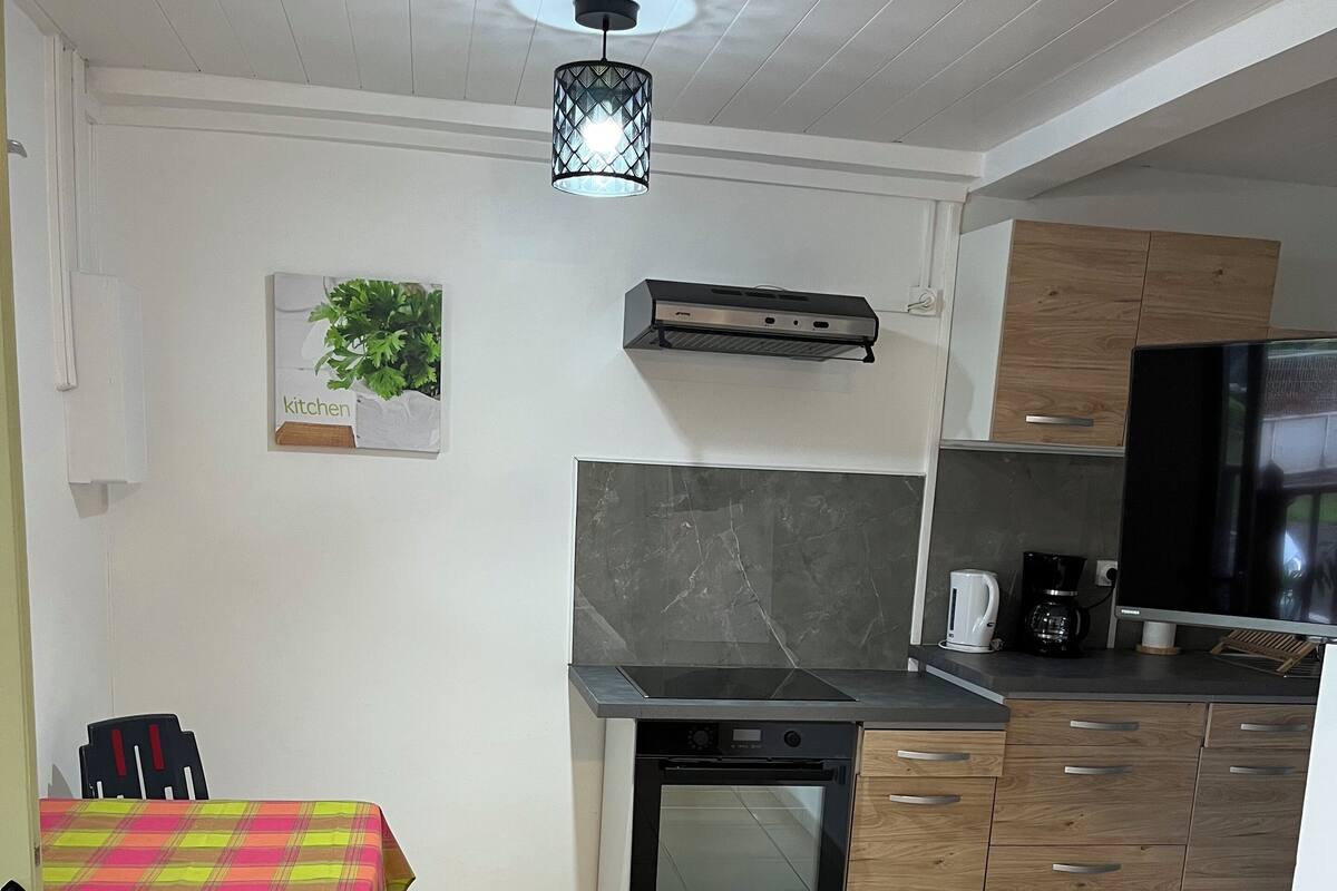 A modern kitchen with a built-in oven, a coffee maker, and a TV.