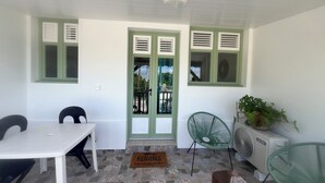 A room with a white table, two chairs, a green chair, a fan, and a potted plant. - Résidence hôtelière Le Manguier Panoramique (Trois-Ilets)