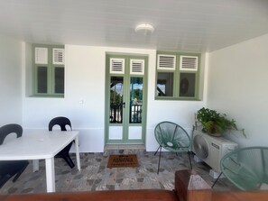 A room with a white table, two chairs, a green chair, a fan, and a potted plant. - Résidence hôtelière Le Manguier Panoramique (Trois-Ilets)