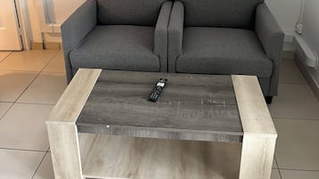 Un sofá gris con una mesa de centro de madera.