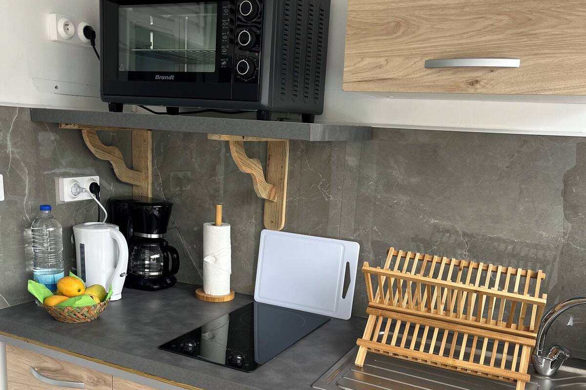 A modern kitchen with a built-in microwave, coffee maker, and a fruit basket.