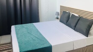 A bedroom with a bed, curtains, a painting, and a ceiling fan. - Résidence hôtelière Le Manguier Panoramique (Trois-Ilets)