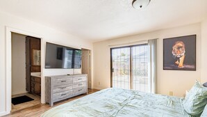 A bedroom with a bed, a dresser, a TV, and a sliding glass door to the outside. - Gated home w/ backyard retreat (Sacramento)