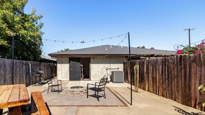 An outdoor patio with picnic tables and chairs, a barbecue grill, and a stone fire pit. - Gated home w/ backyard retreat (Sacramento)