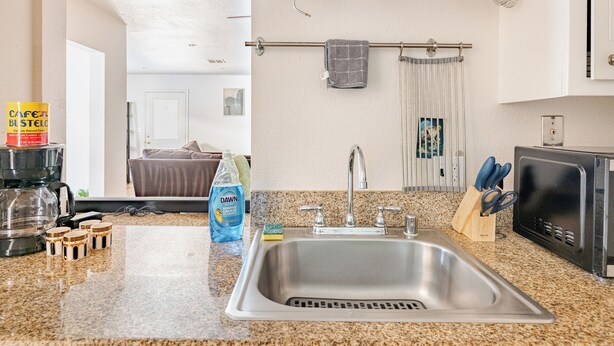 A kitchen with a stainless steel sink, a coffee maker, a bottle of Dawn dish soap, and a knife block. - Gated home w/ backyard retreat (Sacramento)