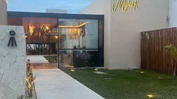 A modern building with a glass facade and a neon sign that reads "Mok".