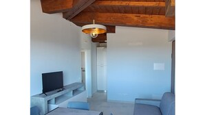 A modern living room with a TV, sofa, and dining area. - Panoramic balcony and breathtaking views, a stone's throw from Lake Bolsena (Montefiascone)