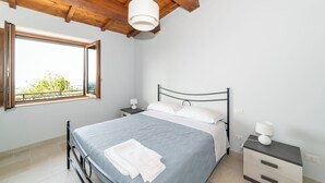 A bedroom with a bed, bedside tables, a window, and a wooden ceiling. - Panoramic balcony and breathtaking views, a stone's throw from Lake Bolsena (Montefiascone)